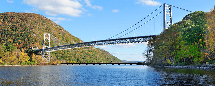 Photograph of a Bridge in the Hudson Valley in NYS surrounded by lush & colorful trees and plants in the fall.